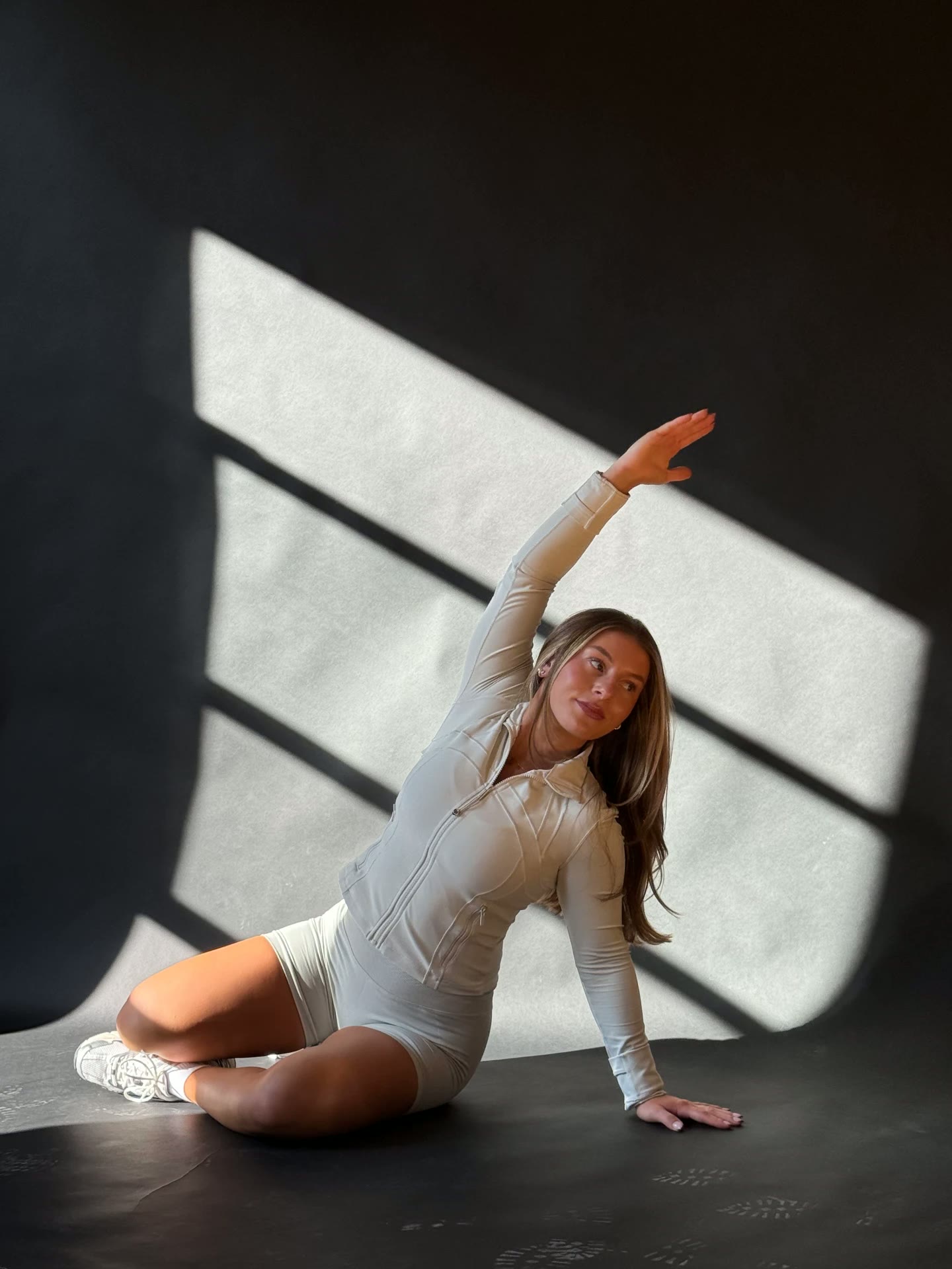 Emma Citarelli in a seated side stretch in a sunlit studio